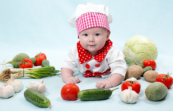 bambino con grembiule tra la verdura fresca